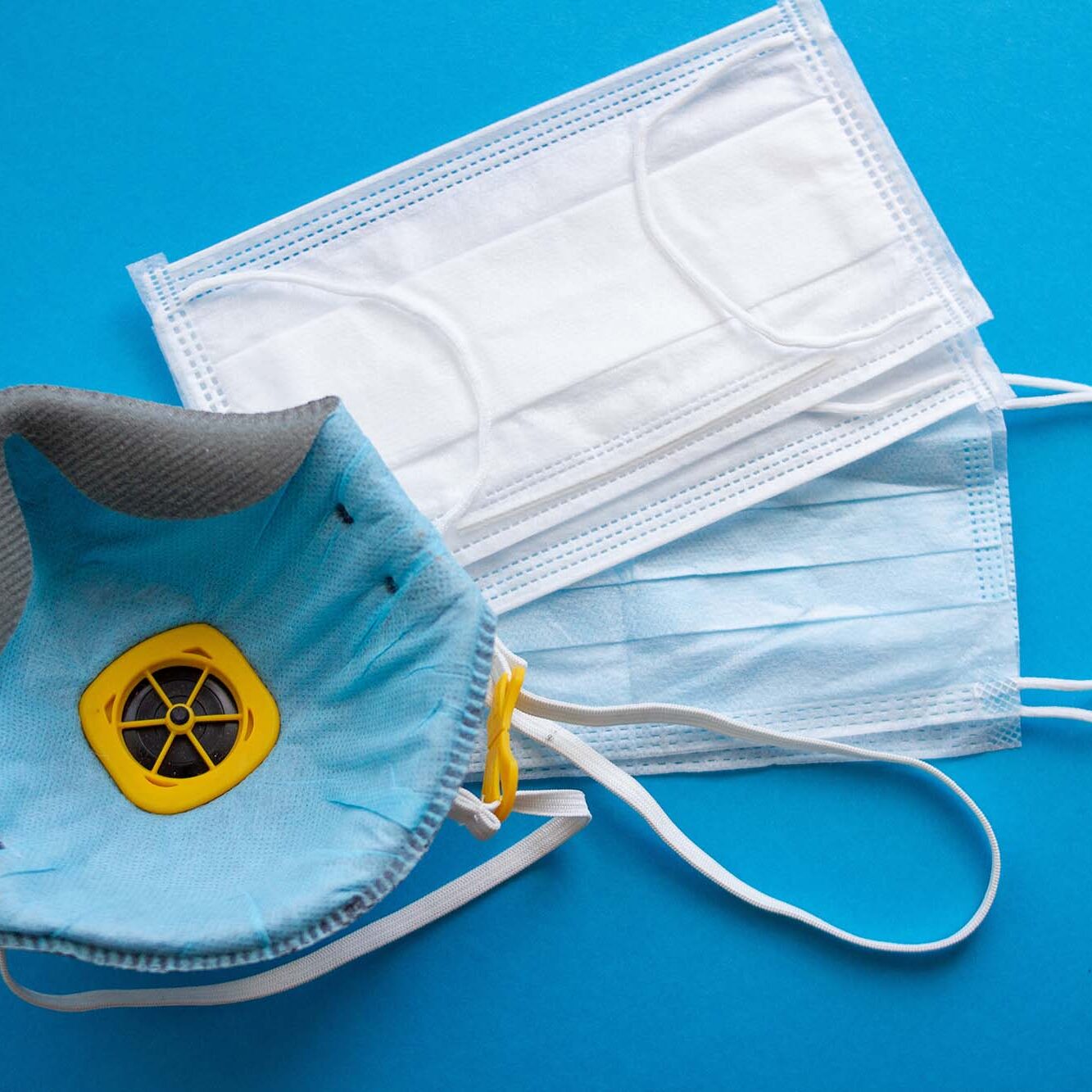 Protective medical face masks and respirator on a blue background Protective medical face masks and respirator on a blue background.